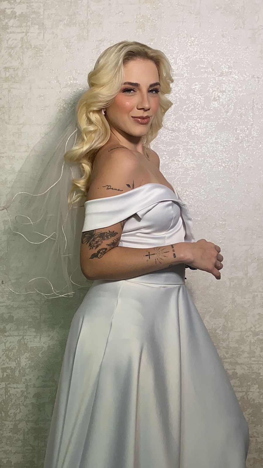 Noiva de perfil com vestido branco acetinado e véu